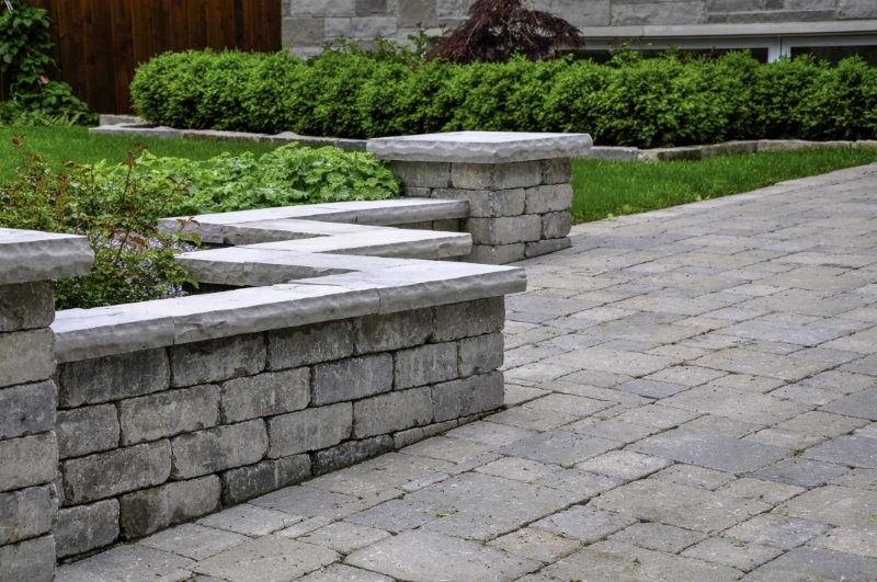 A natural stone retaining wall surrounding a luscious green garden.